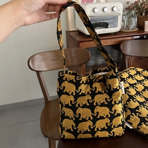 Détail du sac porté épaule en tissu avec motif éléphant doré et étiquette de marque
