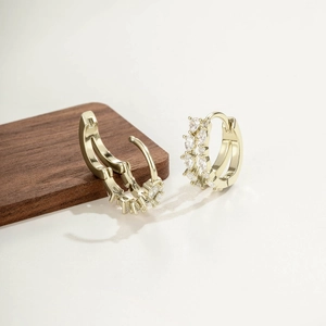 Boucles d'oreilles doubles en or avec zircons transparents sur support en bois