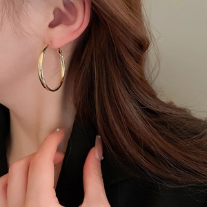 Close-up of elegant gold hoop earrings worn by a model showcasing classic minimalist style