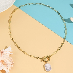 Close-up of Baroque pearl pendant on gold paperclip chain with toggle clasp detail