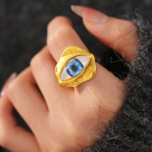 Detail shot of a golden irregular textured ring with a blue evil eye on the finger