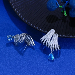 Detailed view of silver hoop earrings with white crystals and blue teardrop stone
