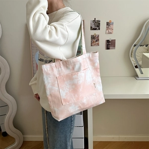 Dettaglio della borsa tote in tela tie-dye rosa con tasca frontale in ambiente domestico