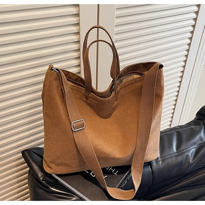 Detail of a brown canvas tote bag featuring adjustable shoulder strap and woven handles