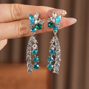 Close-up of vintage silver flower earrings with blue tassels and sparkling rhinestones