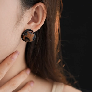 Gros plan d'une boucle d'oreille léopard avec bord noir portée par un mannequin