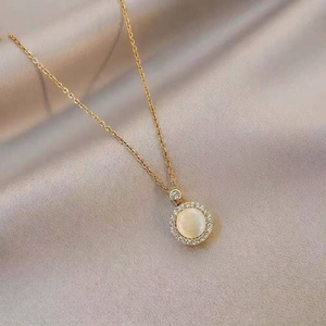 Rotating cat-eye stone necklace with zirconia accents on champagne silk background