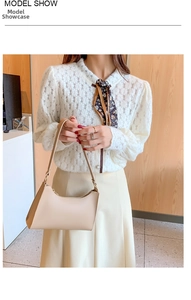 Close-up of beige minimalist underarm bag with gold metal hardware and zipper