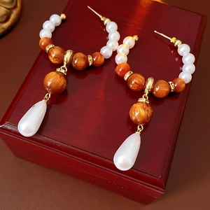 Detail of vintage drop earrings with white pearls and amber beads on a wooden gift box
