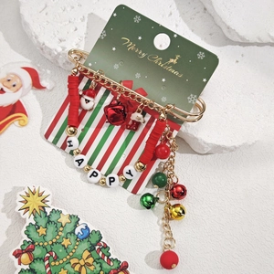 Détail de la broche de Noël avec breloques festives, cloches rouges et glands dorés