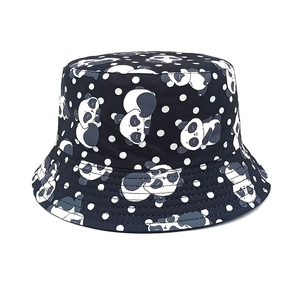 Detail of baby bucket hat featuring cartoon panda patterns and white polka dots on black fabric