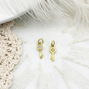 Detailed view of two gold key charms featuring zircon inlays and hollow mesh patterns