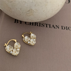 Detail of 18k gold plated heart hoop earrings featuring white flowers and zircon accents