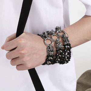 Detail of woven leather bracelets with wolf, skull, and dragon heads on man wrist
