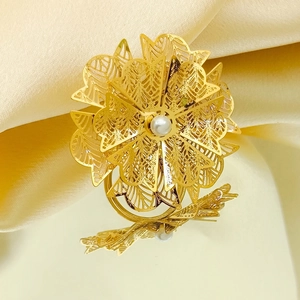Macro shot of 3D layered golden flower ring with central pearl on silk background