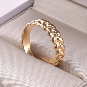 Close-up of golden braided texture ring with polished finish on a display stand