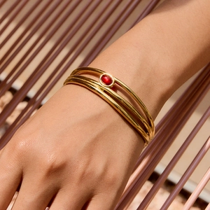 Bracciale rigido a tre strati in acciaio dorato con pietra cabochon ovale rossa centrale