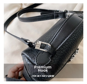 Close-up of black crocodile texture leather bag with silver metal hook and adjustable strap
