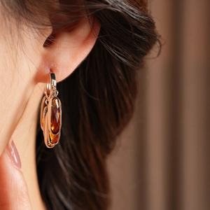 Gros plan d'un mannequin portant des boucles d'oreilles vintage en verre ambré doré