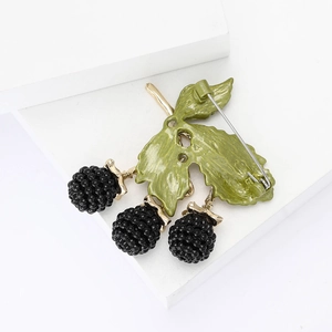 Detailed close-up of a creative blackberry brooch with black beads and green enamel leaves