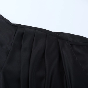 Macro shot of elegant black satin fabric featuring intricate pleated folds and silky texture