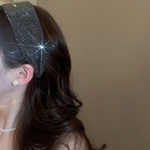 Detail of wide black headband with shimmering rhinestones worn on hair with elegance