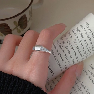 Irregular silver 925 minimalist croissant twist ring shown on a finger with lifestyle props