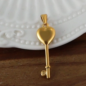 Détail macro d'un pendentif clé plaqué or 24 carats avec un design de cœur sur le dessus