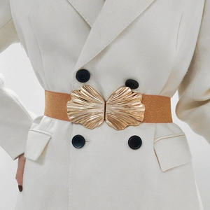 Detail eines braunen Stretchgürtels mit goldener Muschelschnalle auf weißem Blazer
