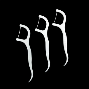 Detailed macro view of three white plastic dental floss picks against a black background