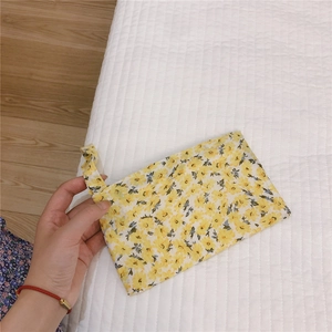 Détail de la pochette en coton à fleurs jaunes avec dragonne assortie sur tissu