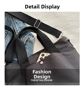 Detalle de un bolso tote de nailon negro con bolsillo frontal funcional y correa ajustable
