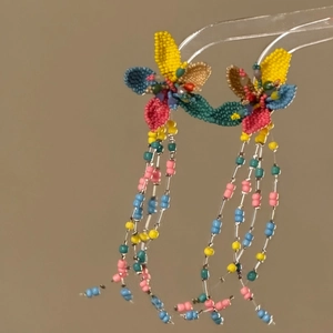 Macro view of vibrant colorful beaded flower earrings with long hanging bead tassels
