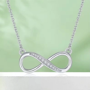 S925 sterling silver infinity pendant necklace with white diamonds on a soft green background