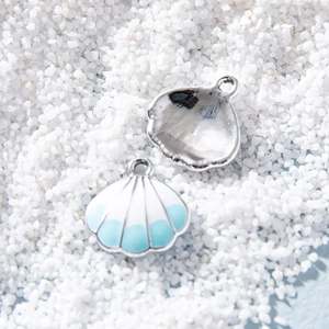 Ocean shell pendant in blue and white enamel on white sand, minimalist beach charm