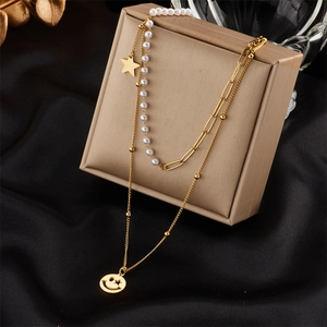Double-layer gold necklace with pearls, stars and smiley face charms on beige gift box