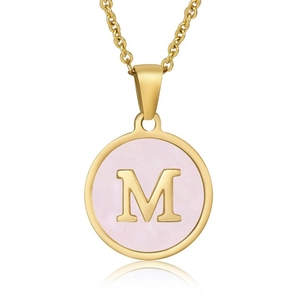Close-up of golden necklace pendant with letter M on pink mother of pearl shell