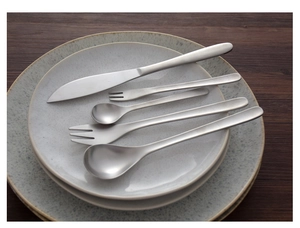 Five-piece matte 304 stainless steel cutlery set on ceramic plates and dark wood