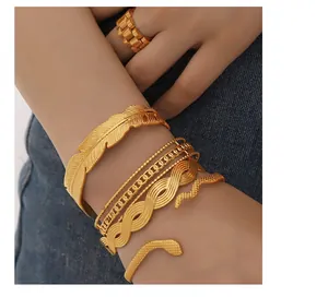 Detail of vintage 18K gold plated Cuban chain and feather bangles set on blue denim
