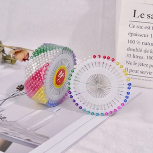 Macro shot of colorful round pearl head pins neatly arranged in a white plastic disc holder