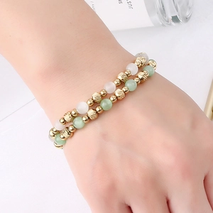 Elegant beaded bracelet with green stones and gold spiral beads on woman's wrist