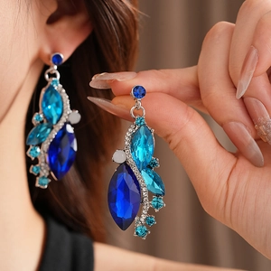 Macro detail of vintage diamond-set rhombus earrings with blue crystals on ear