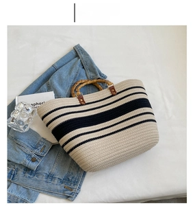 Close-up of woven tote bag with striped pattern and natural bamboo handles on fabric