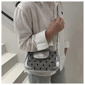 Détail du sac à bandoulière gris à pois avec bordure argentée et motif de nœud