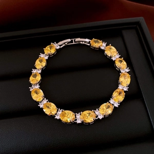 Détail d'un bracelet en pierre ovale jaune et zircons blancs sur coffret en cuir noir