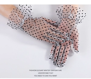 Close-up of white lace gloves with black polka dots and elegant ruffled cuffs for women