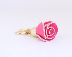 Gros plan d'un porte-clés rose en cuir avec un anneau doré poli sur fond blanc épuré