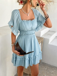 Close-up of blue short-sleeved dress with square neckline and ruffle edges at a beach setting