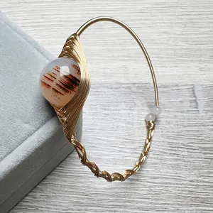 Detail of handmade 14K gold-wrapped wire bracelet featuring a landscape agate bead