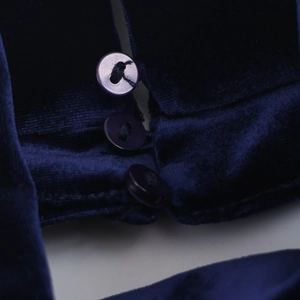 Detail of dark blue velvet maxi dress showing soft fabric texture and button closure